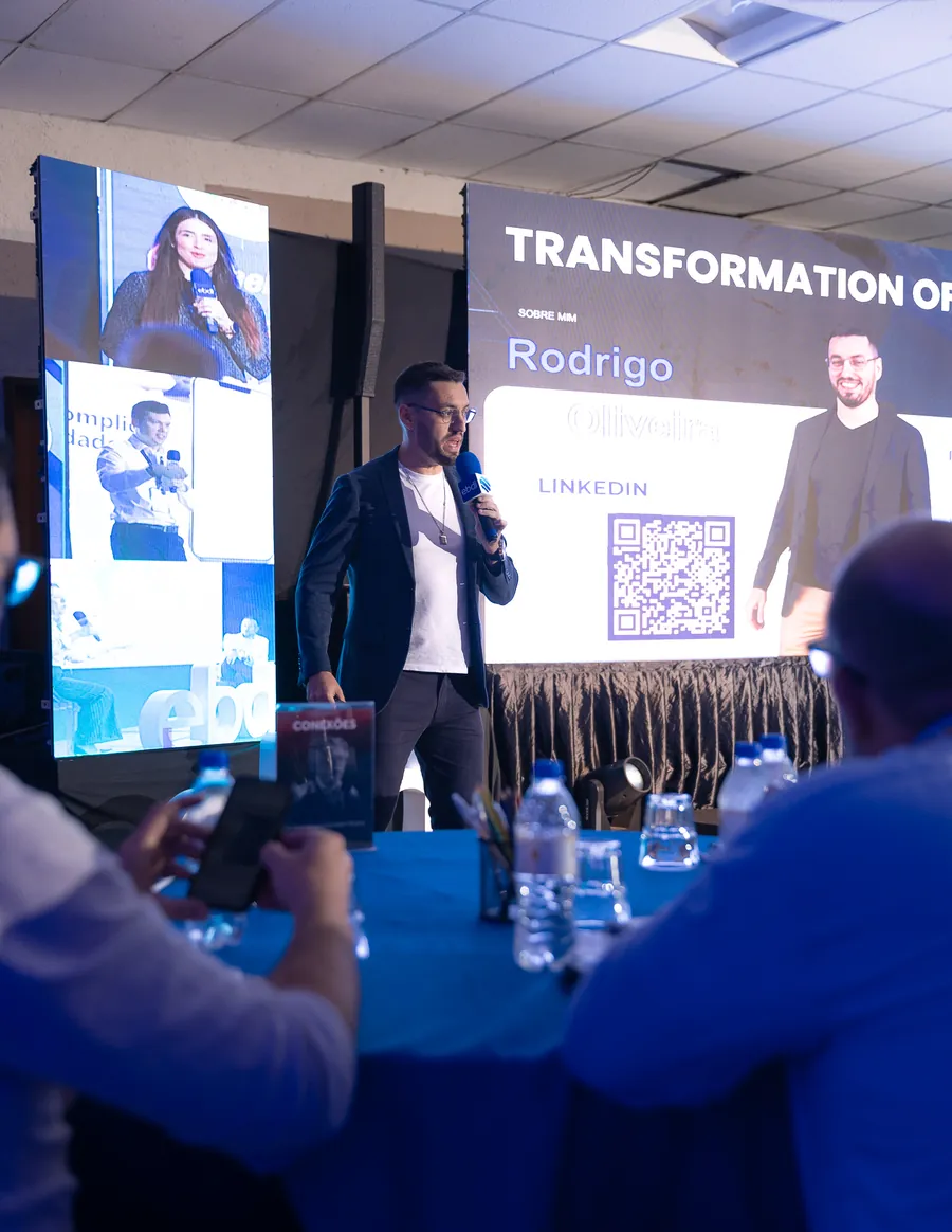 Palestrante no palco principal com o painel de LED